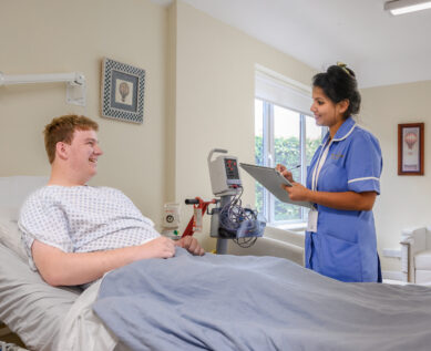 A nurse talks with a patient in their private room